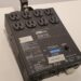 A black Elation Professional ED15 dimmer pack with multiple electrical outlets, labeled controls, and buttons is placed on a white surface. The device has various input and output sockets with attached labels and a handle on top.