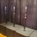 Three microphone stands are positioned on top of speaker cabinets in front of a black curtain backdrop. The stands are evenly spaced and have similar designs, with adjustable height sections.