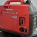 The image shows a red Honda EU2000i portable generator featuring Cold Climate Technology and various control knobs on a gray background.
