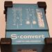 Close-up of a blue Samson S-convert audio converter device, featuring diagrams and text indicating -10dBV to +4dBu. The device has four corner protectors and technical illustration on its surface.