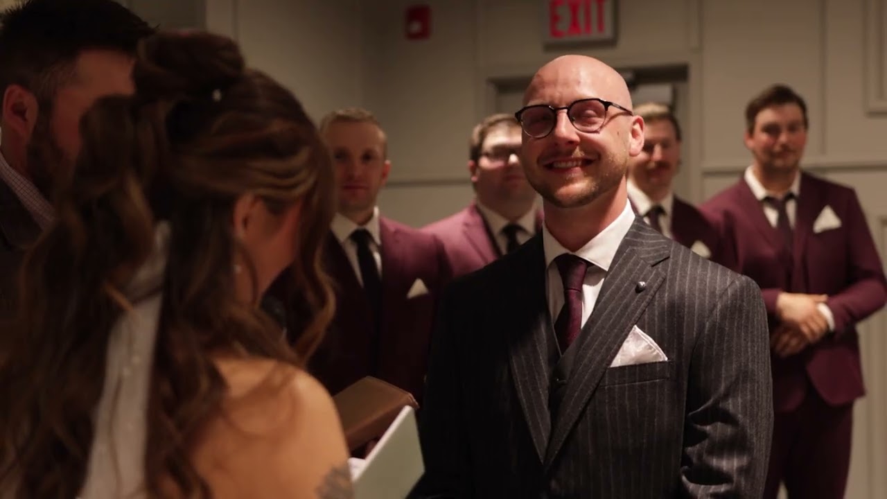 At this Spring Wedding 2026, Tristin and Cass share a joyful moment as the groom in a striped suit smiles warmly at his bride, with groomsmen in matching burgundy suits standing behind them.