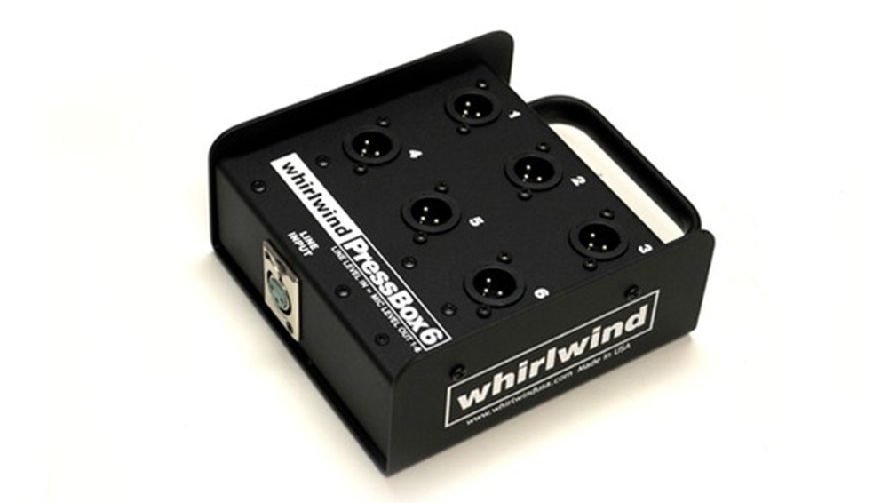 A black Whirlwind Press Box 6 with six numbered XLR output ports, a metal handle, and a labeled panel, used for audio signal distribution.
